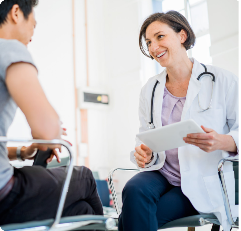 Image of female doctor in white lab coat holding a tablet, discussing health results with a patient.